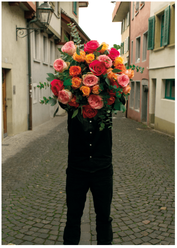 Ein Mann, der einen Rosenstrauss von Linder Blumen Aarau in der Hand hält.